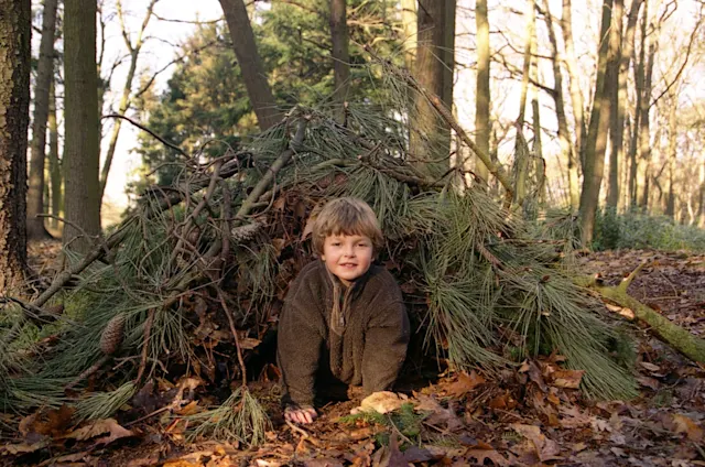 Ranger inside a debris hut survival shelter