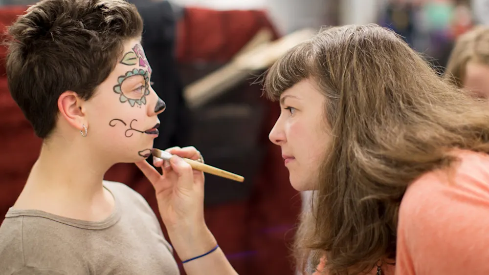 Trackers Guide painting a sugar-skull design on a kid at Track-or-Treat