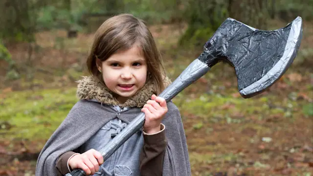 Costumed kid holding an axe in the forest