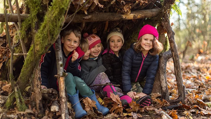 Campers in winter hats inside a debris shelter at winter camp