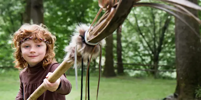 Kid holding a staff with a skull on it in the forest